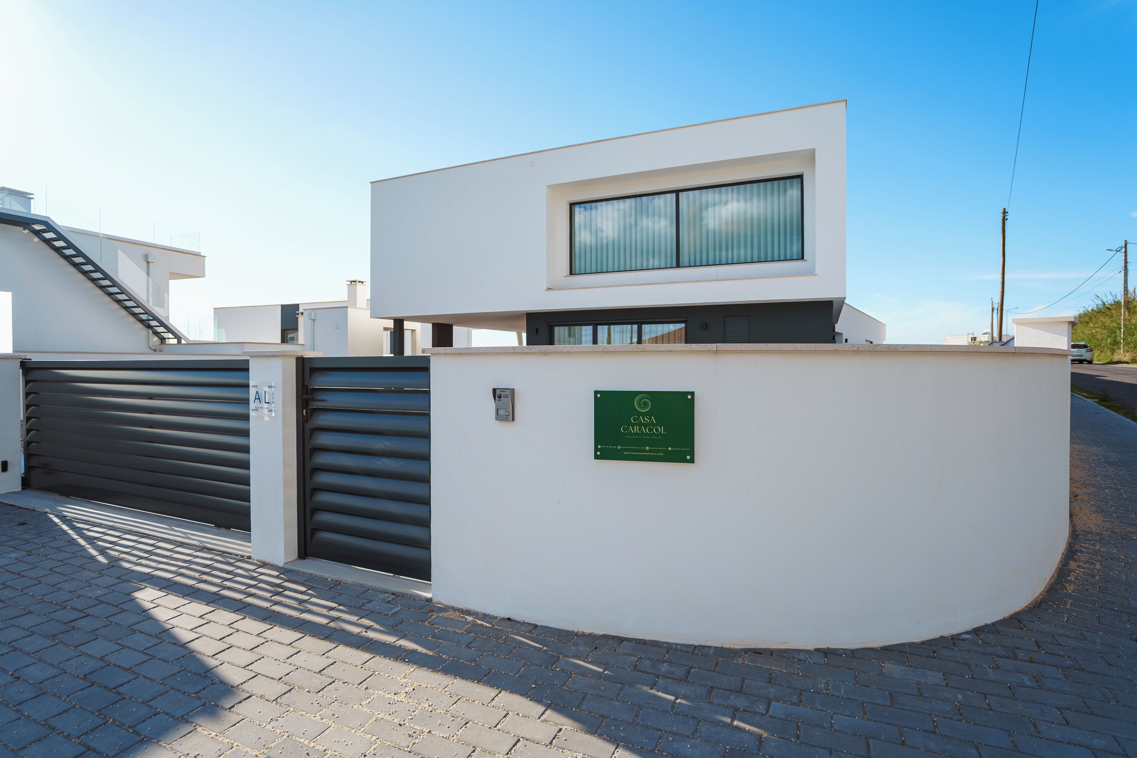 Un edificio moderno con facciata bianca, un'ampia finestra e un portone garage chiuso.