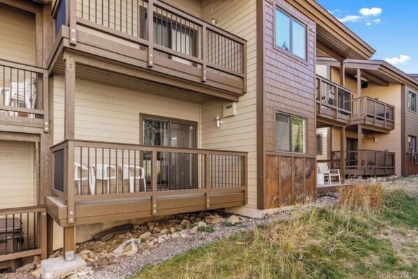 A multi-story residential building with balconies, a stone foundation, and a clear sky. - Big Sky Ski in- Ski out retreat/ Freshly Remodeled (Big Sky)
