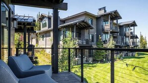 Ein modernes Mehrfamilienhaus mit Balkon, Sitzgelegenheit im Freien und einem gepflegten Rasen.