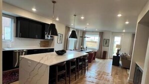 A modern kitchen with a central island, wooden flooring, and pendant lighting. - Very cozy copper John, town center retreat! (Big Sky)