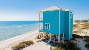 A turquoise lifeguard tower with a balcony, situated on a sandy beach with the ocean in the background. - Beachfront Escape | Pet Friendly | Fort Morgan (Gulf Shores)