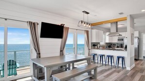A modern kitchen with a large island, bar stools, and a view of the ocean. - Beachfront Escape | Pet Friendly | Fort Morgan (Gulf Shores)