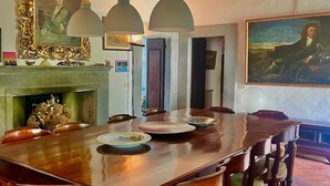 A dining room with a large wooden table, chairs, and hanging pendant lights. - The Ancient Farmhouse in Caiano – a dive into history, books, nature. (Toscana)