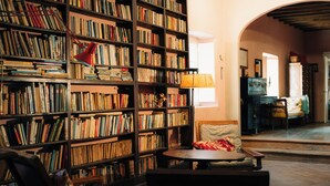A library with bookshelves, a reading chair, and a lamp. - The Ancient Farmhouse in Caiano – a dive into history, books, nature. (Toscana)