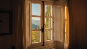 A room with a large window, curtains, and a radiator. - The Ancient Farmhouse in Caiano – a dive into history, books, nature. (Toscana)