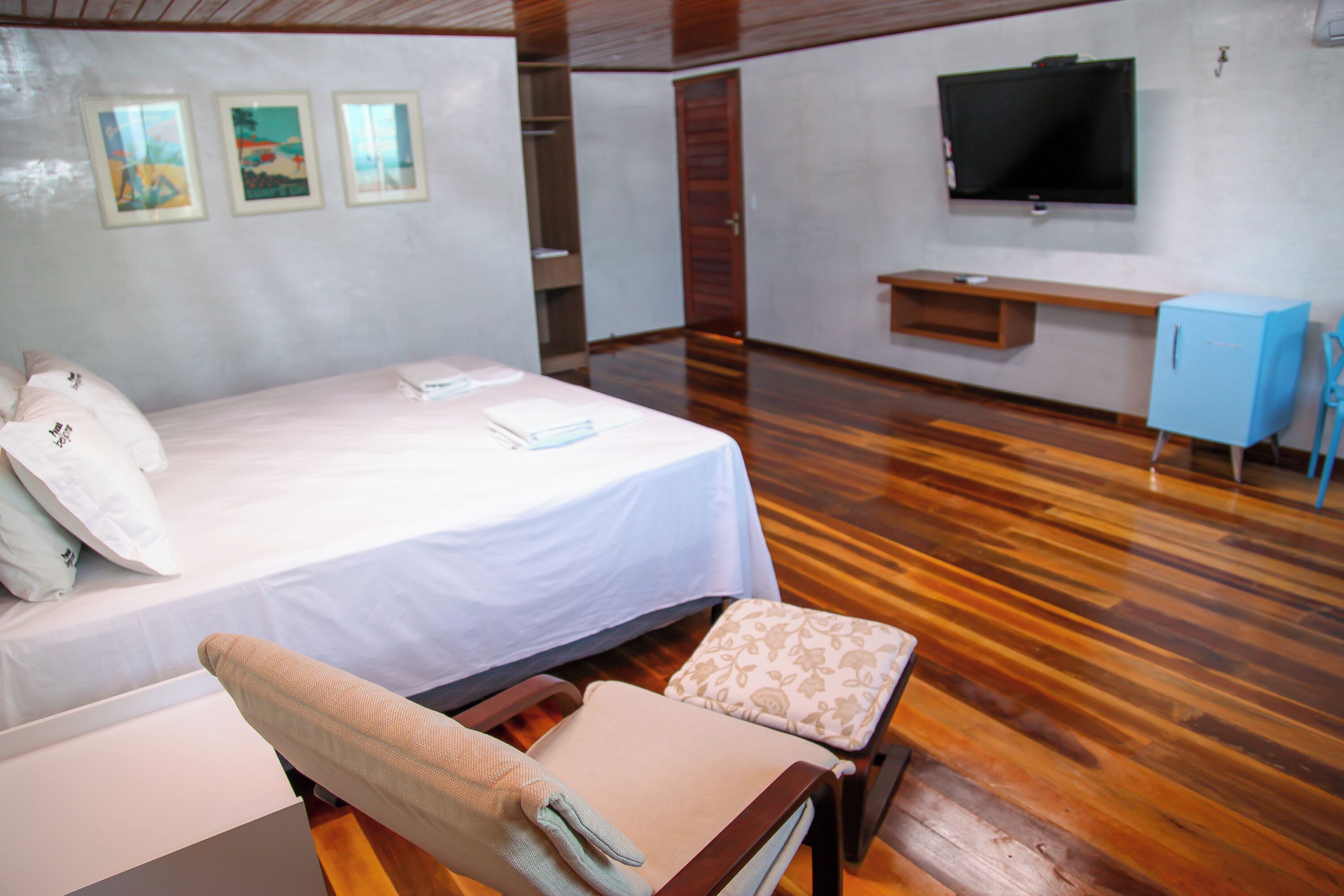 A hotel room with a bed, a chair, a television, and a desk.