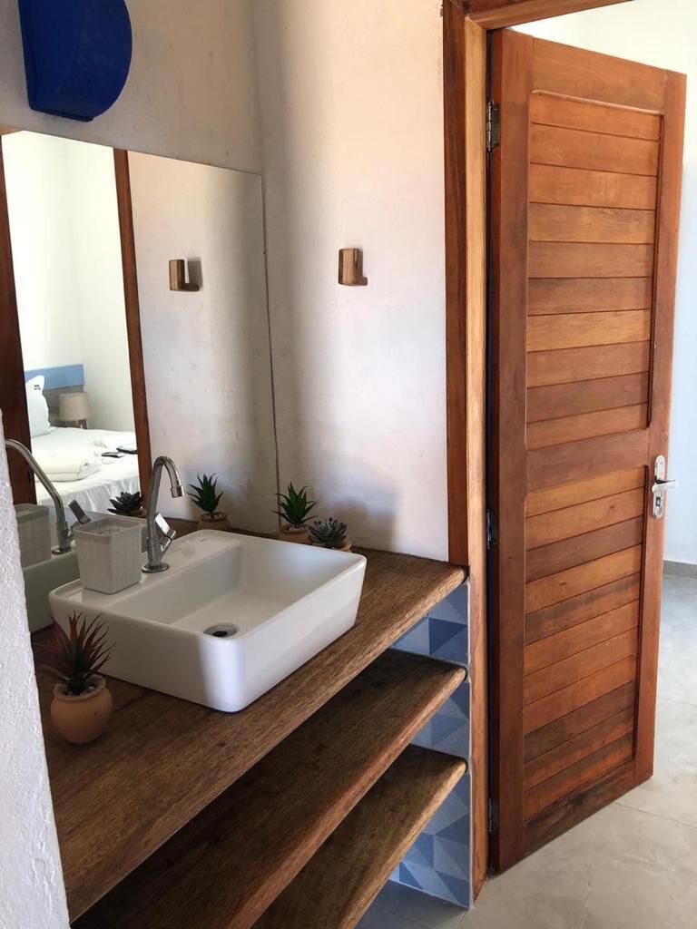 A bathroom with a white sink, wooden shelves, and a wooden door.