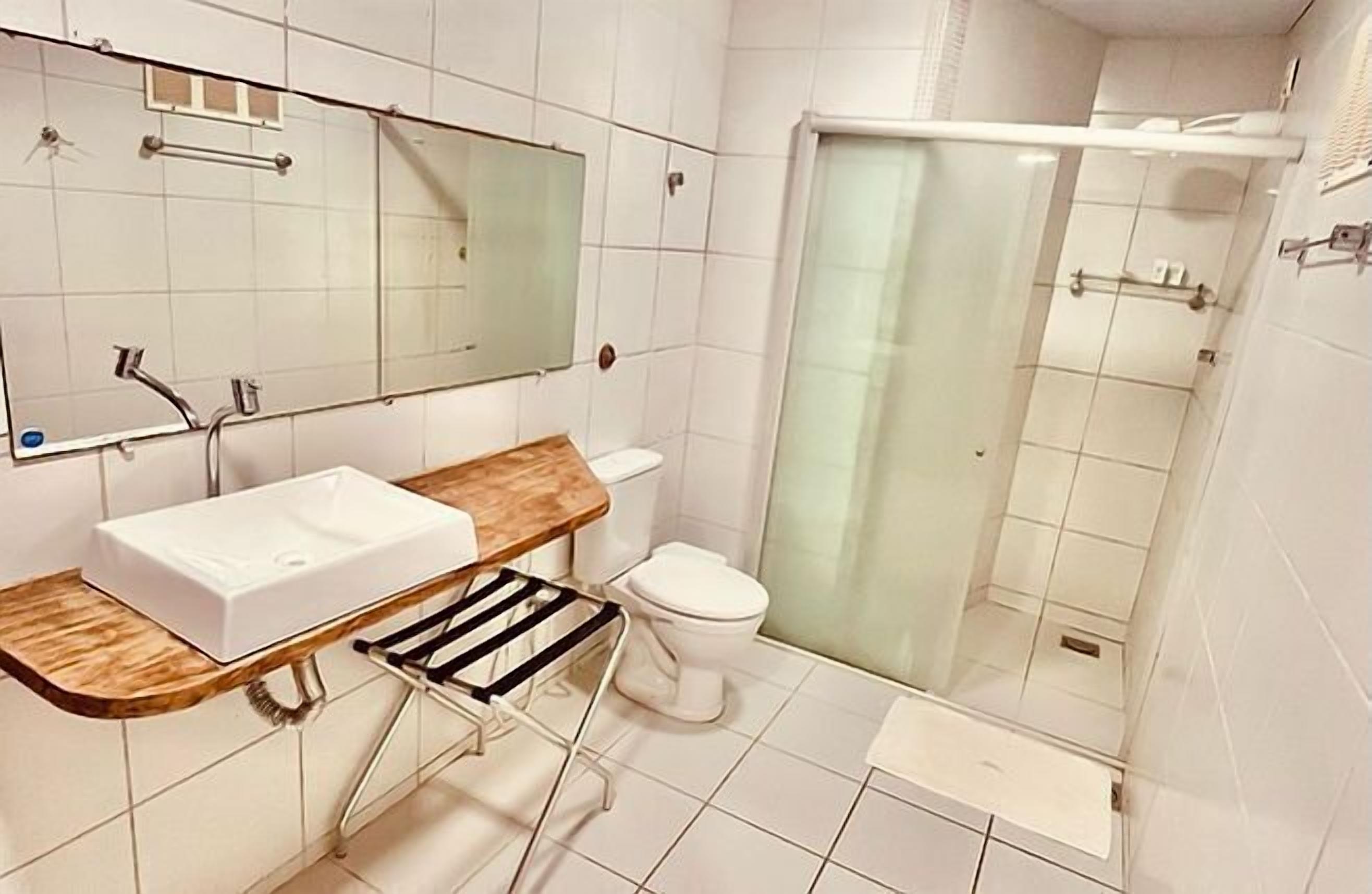 A bathroom with a white sink, mirror, and toilet.