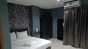 A modern hotel room with a large bed, a wardrobe, a bedside table with a lamp, and an air conditioning unit. - Central Perk Hotel (Patong)
