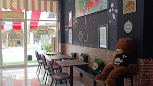 A cafe interior with a mural, seating, and a teddy bear. - Central Perk Hotel (Patong)