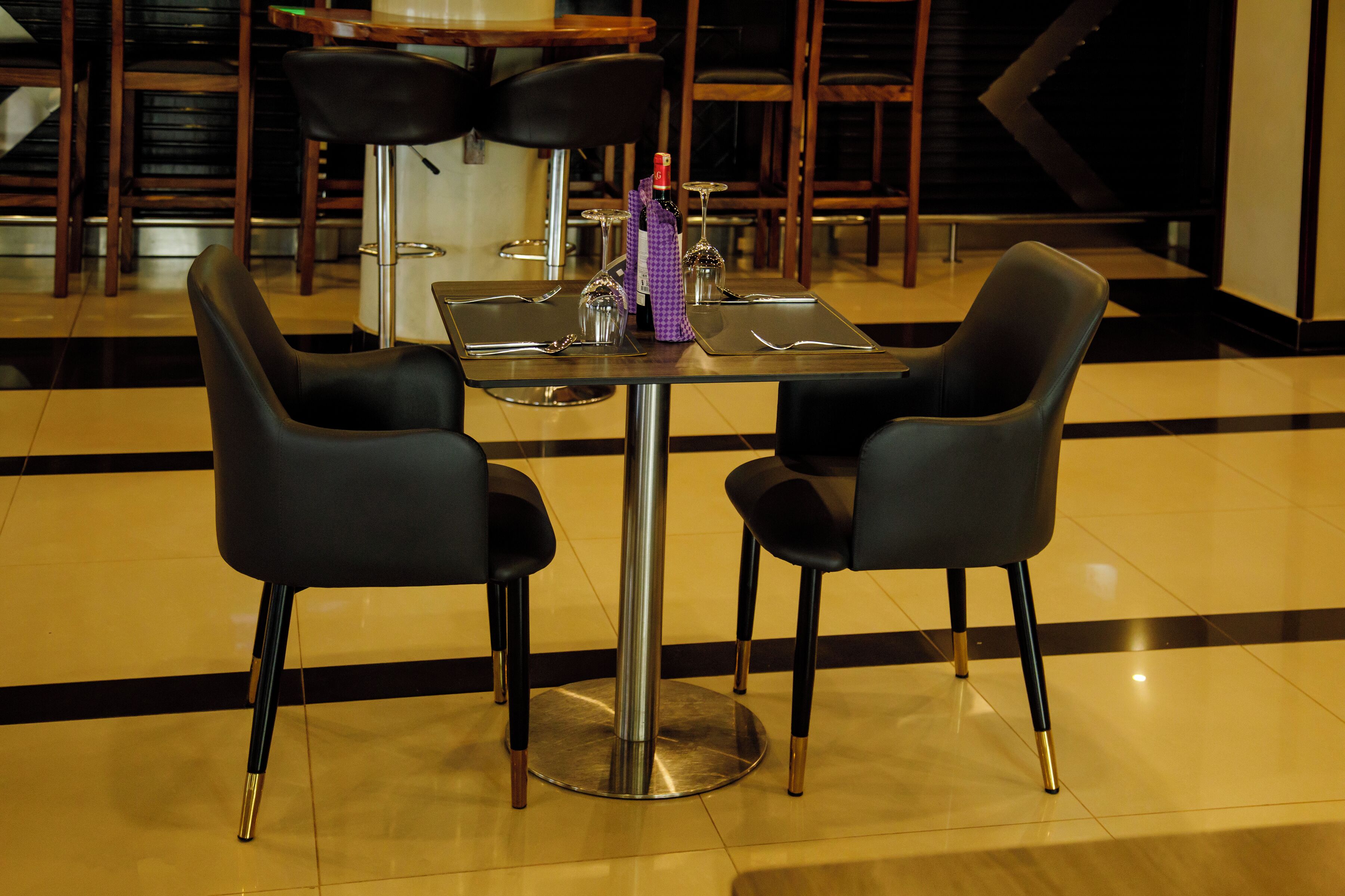 A dining area with a table and two chairs, a bottle, and a wine glass.