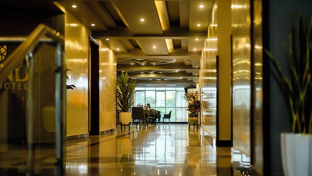 A hotel lobby with a staircase, a reception desk, and a view of the outdoors. - The Grand Plaza Hotel (Kampala)