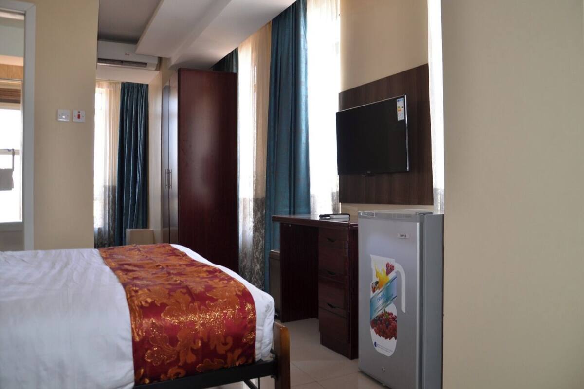 Ein Hotelzimmer mit Bett, Schreibtisch, Fernseher und Kühlschrank.