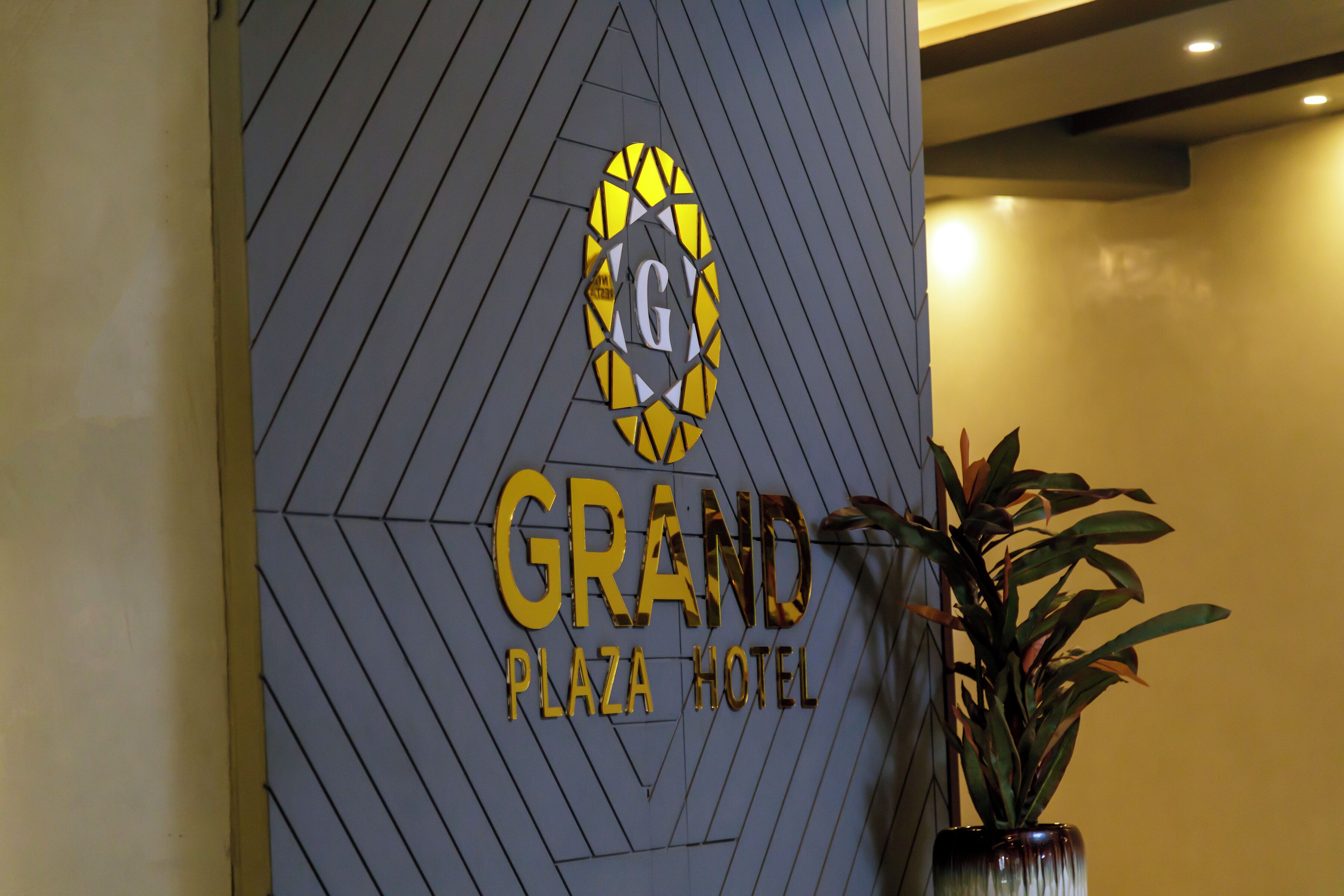 A hotel sign with a geometric pattern and the name 'GRAND PLAZA HOTEL'.