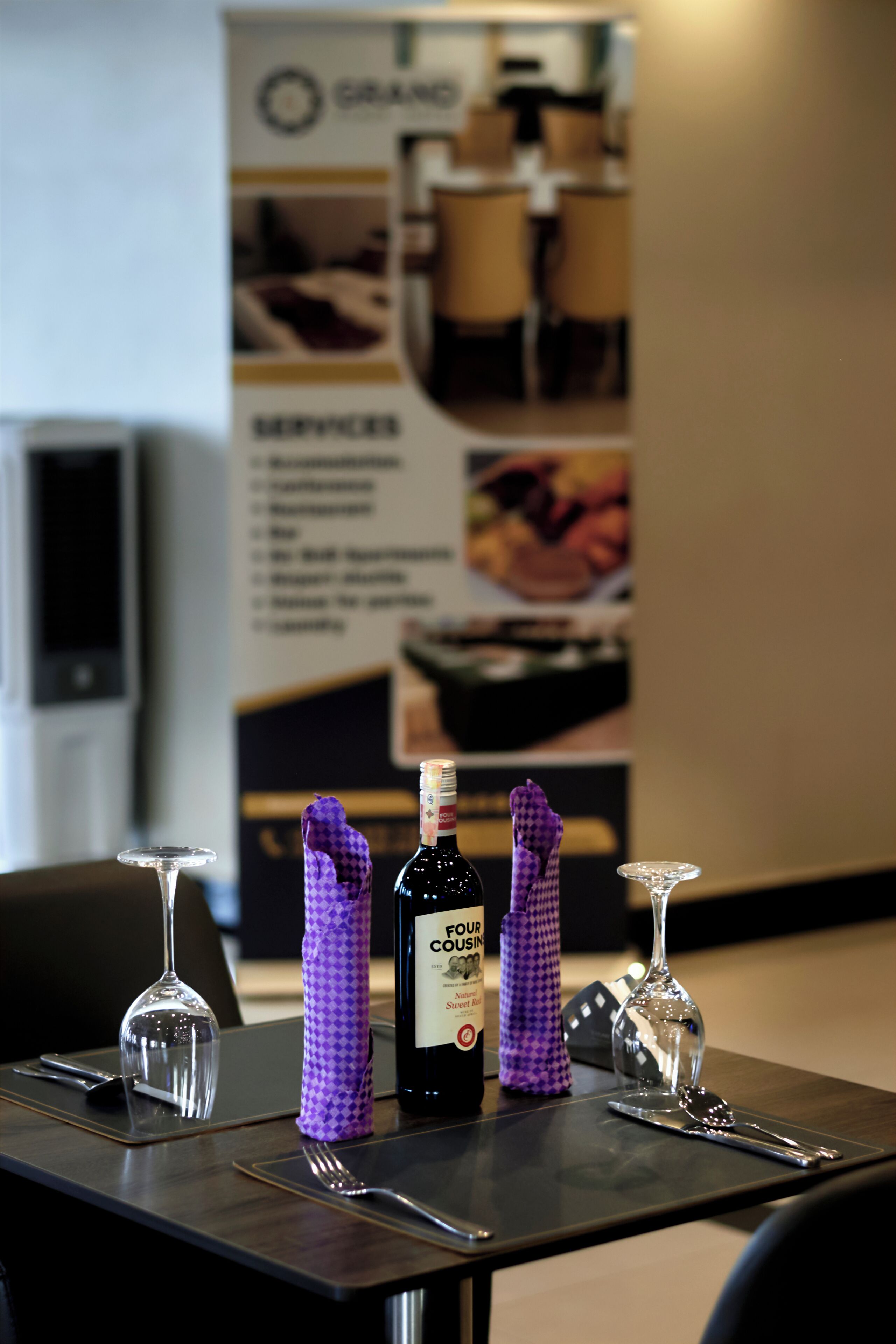 A table set with a bottle of Four Seasons wine, a purple napkin, and a wine glass.