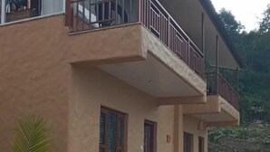 Un bâtiment à deux étages, doté d’un balcon à l’étage supérieur, d’un petit porche au rez-de-chaussée et d’un chemin de pierre menant à l’entrée.