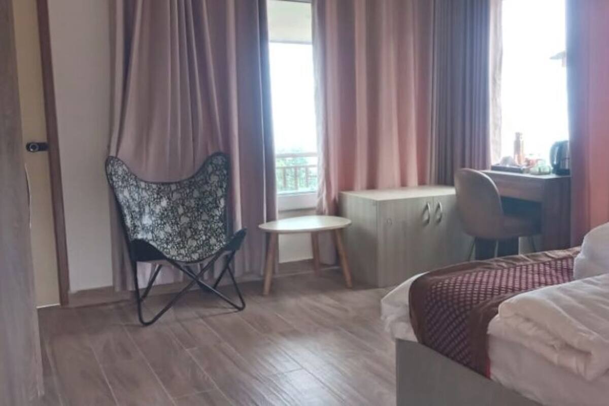 Una habitación de hotel con una cama, un escritorio, una silla y una ventana con cortinas.