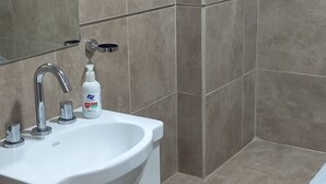 Ein Badezimmer mit Waschbecken, Spiegel und Duschbereich.