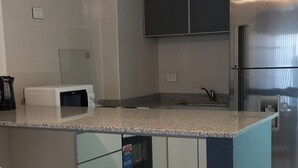 Eine moderne Küche mit einer zentralen Kochinsel, weißen Barhocker und einem Edelstahl-Kühlschrank.