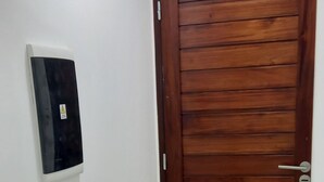 Ein Korridor mit einer Holztür und einem an der Wand montierten Thermostat.
