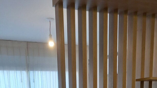 Ein Zimmer mit einem Bett, einer Holzwand und einer Lampe.