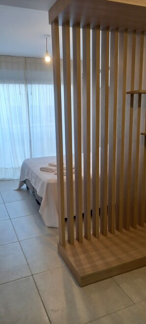 A room with a bed, a wooden partition, and a light fixture. - Monoambiente Centrico (Salta)