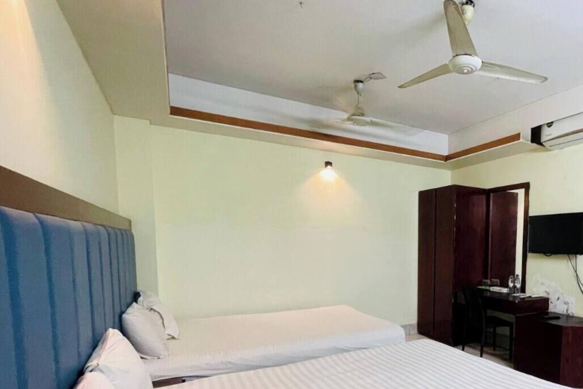 A hotel room with two beds, a ceiling fan, a desk with a chair, and a TV mounted on the wall.