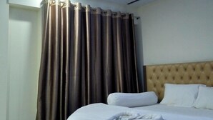 A hotel room with a bed, curtains, and a ceiling light. - Urmee Guest House Coxs Bazar (Cox's Bazar)