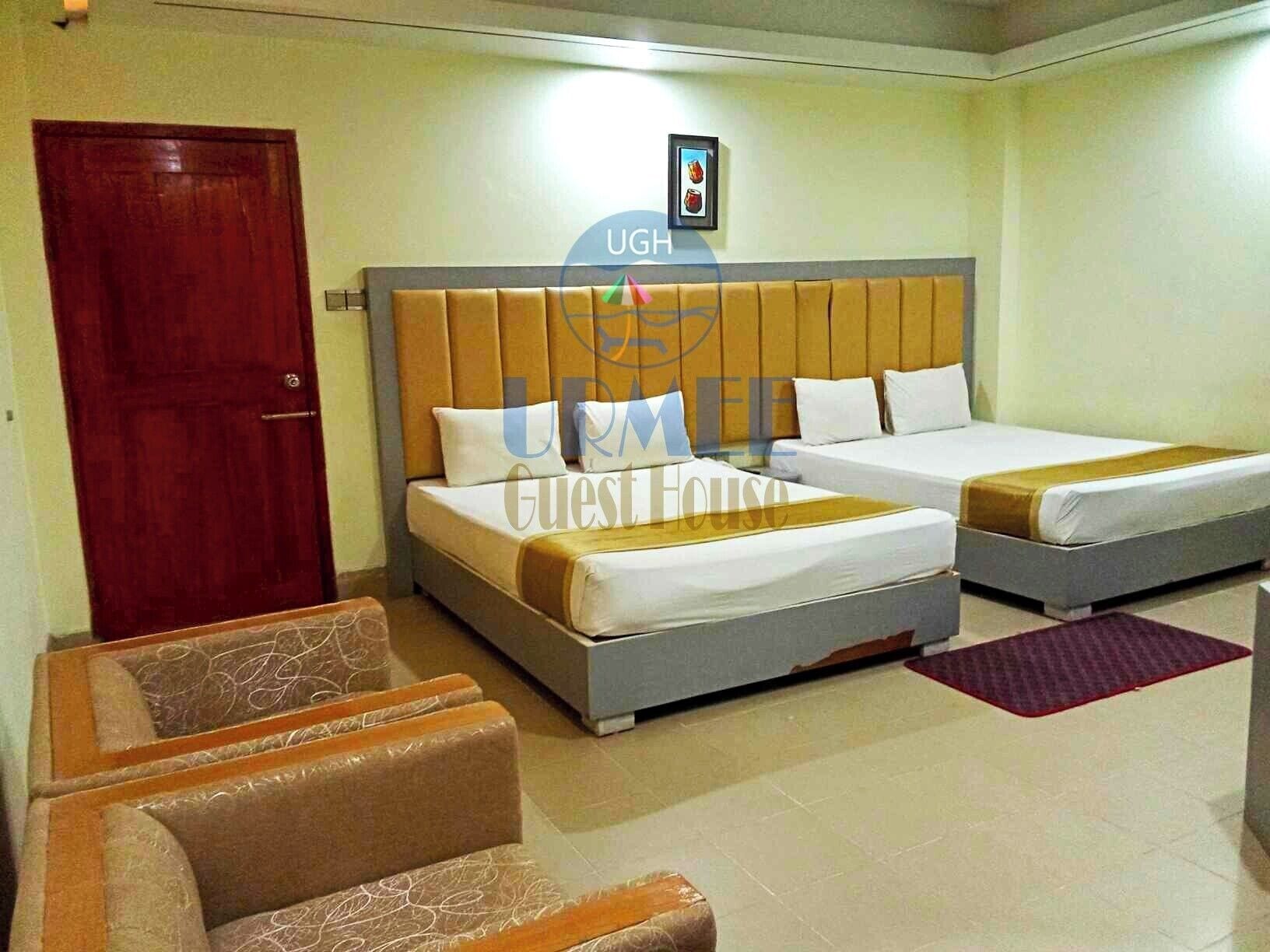 A guest house with two beds, a wooden door, and a framed picture on the wall.