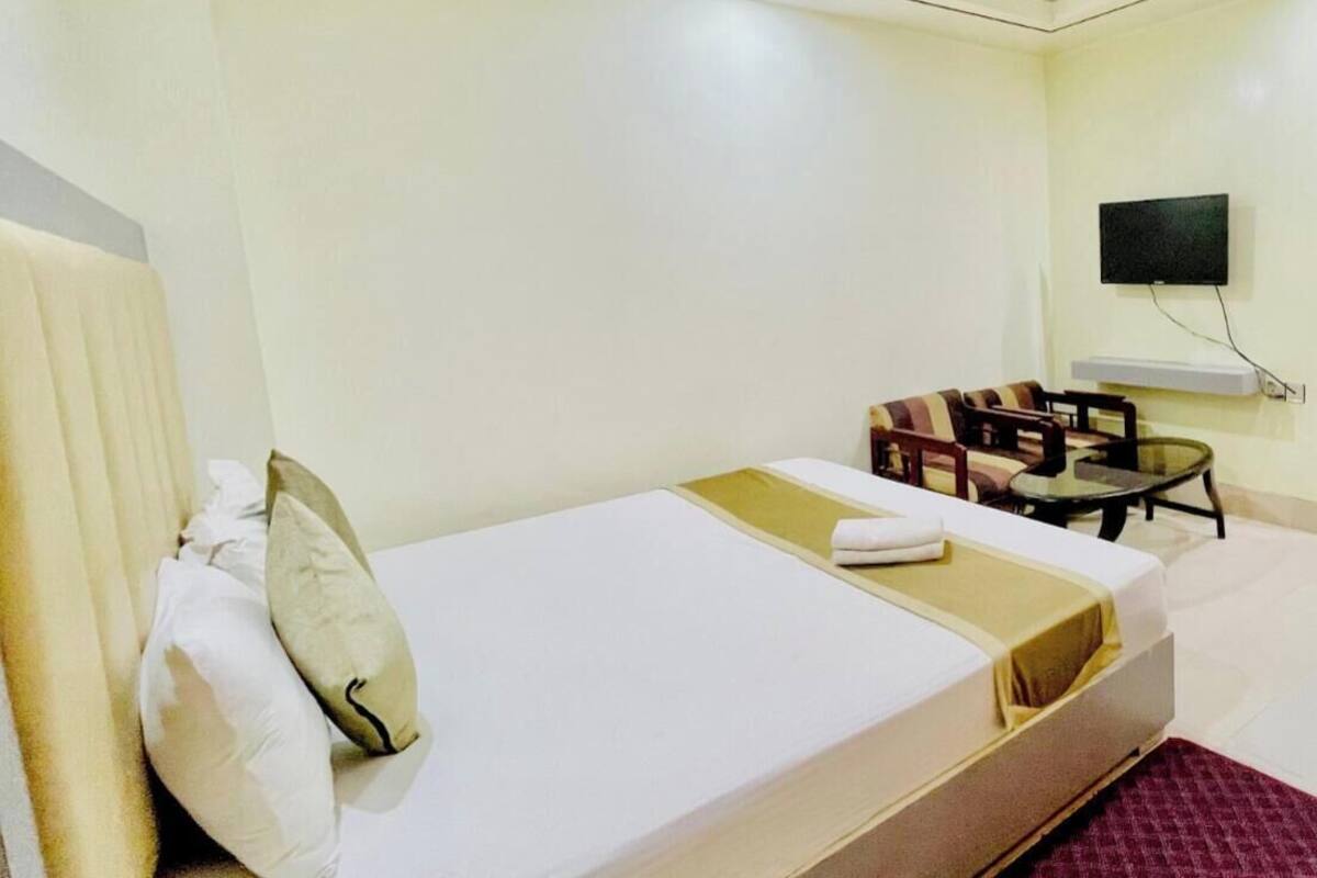 A hotel room with a bed, a sofa, a TV, and a small table.