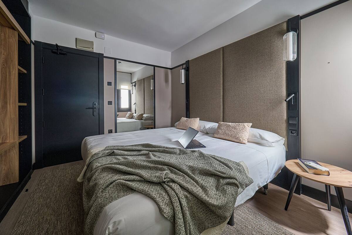 Een moderne hotelkamer met een groot bed, een bureau en een kledingkast.
