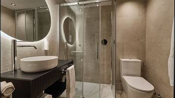 A modern bathroom with a glass-enclosed shower, a white sink, and a toilet.