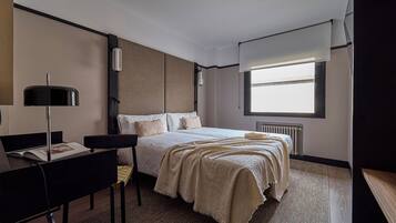 Una habitación de hotel moderna con una cama grande, un escritorio y una ventana con persianas.