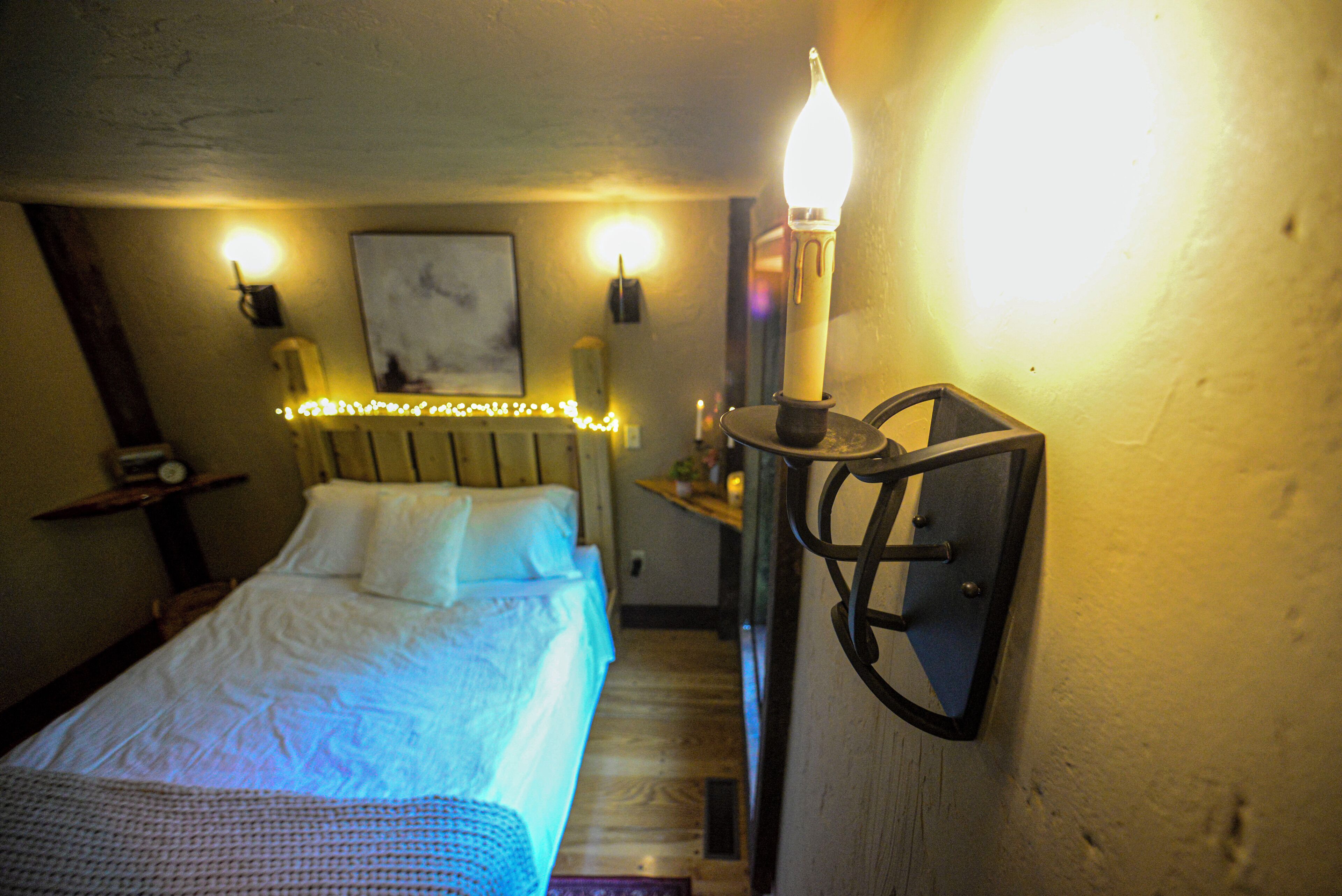 A bedroom with a bed, bedside lamps, and a wall-mounted light fixture.