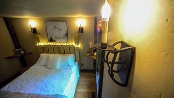 A bedroom with a bed, bedside lamps, and a wall-mounted light fixture.