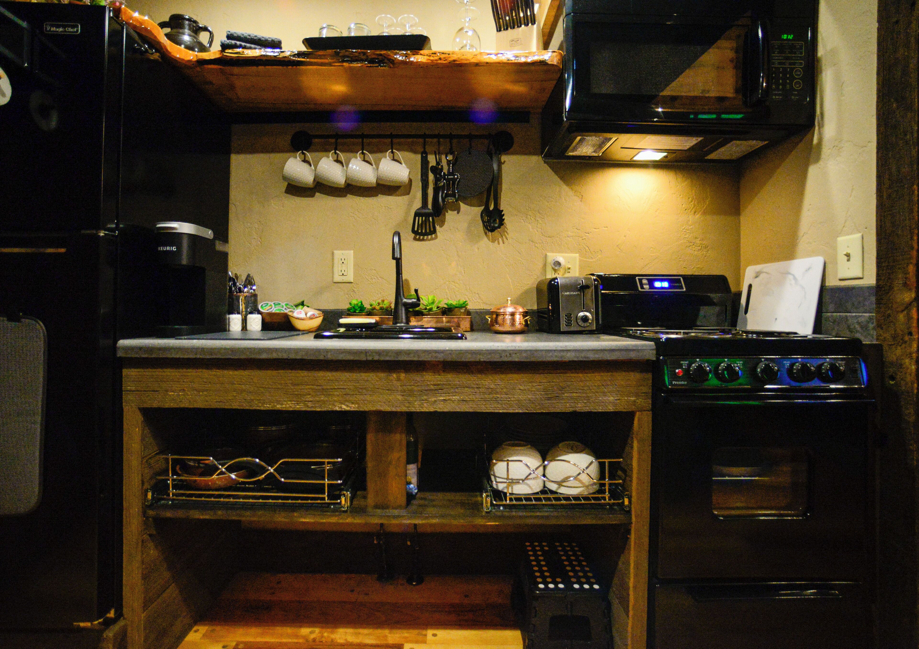 Eine kompakte Küche mit Kaffeemaschine, Toaster, Mikrowelle und Backofen.