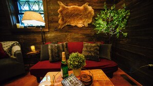 Una habitación acogedora con una pared de madera, un sofá rojo, una mesita con una botella, un libro y una planta.