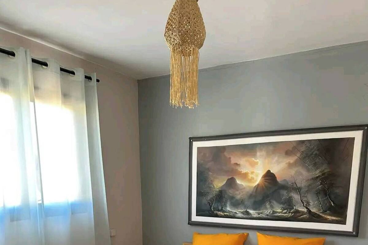 A bedroom with a bed, a painting, and a nightstand.