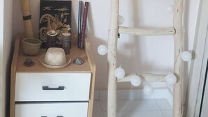 A wooden ladder with white spherical decorations against a wall, next to a bedside table with a framed picture, a bowl, and a small statue. - Auberge Iorenantsoa (Talata Volonondry)