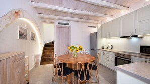 A modern kitchen with white cabinets, a built-in oven, and a dining area with a round table and chairs.