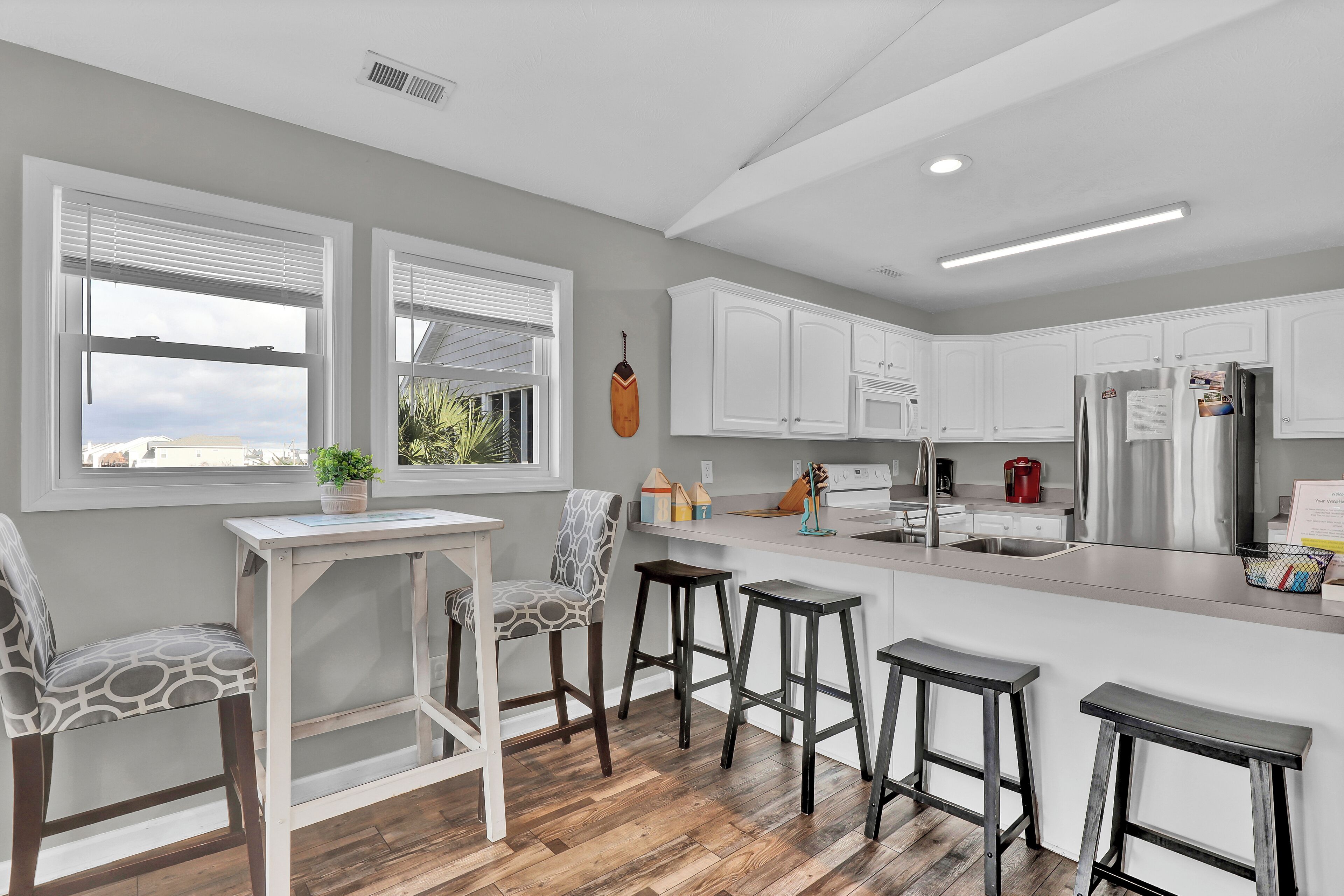 A modern kitchen with white cabinetry, a wooden countertop, and a built-in island with bar stools.