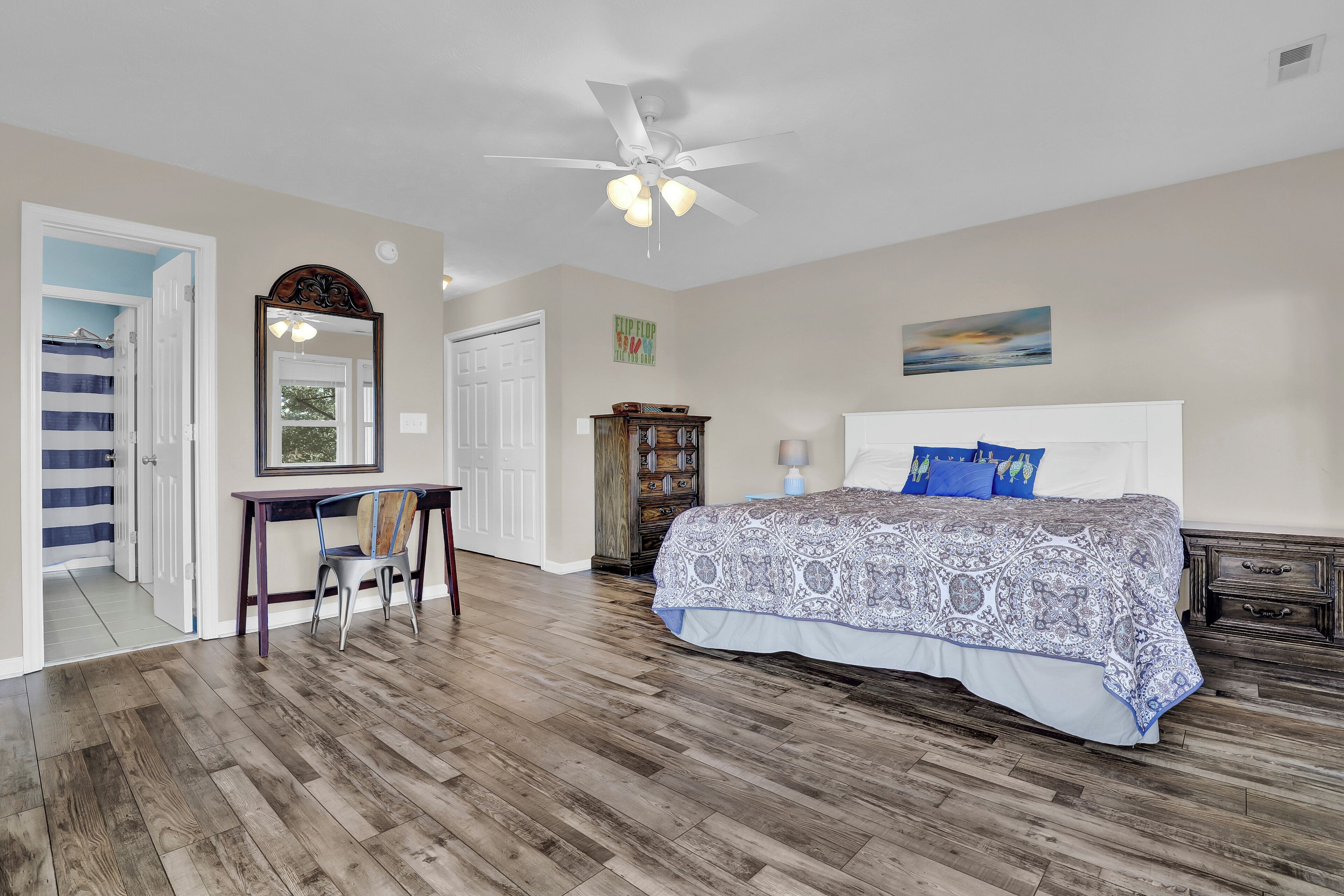A bedroom with a bed, desk, chair, wardrobe, and ceiling fan.