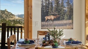 Een eettafel gedekt voor twee met een prachtig uitzicht op een berg en een eland.