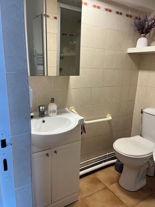 Un baño con lavamanos, espejo y retrete blancos.
