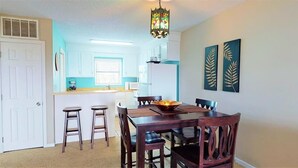 A dining area with a wooden table and chairs, a chandelier, and two wall-mounted artworks.
