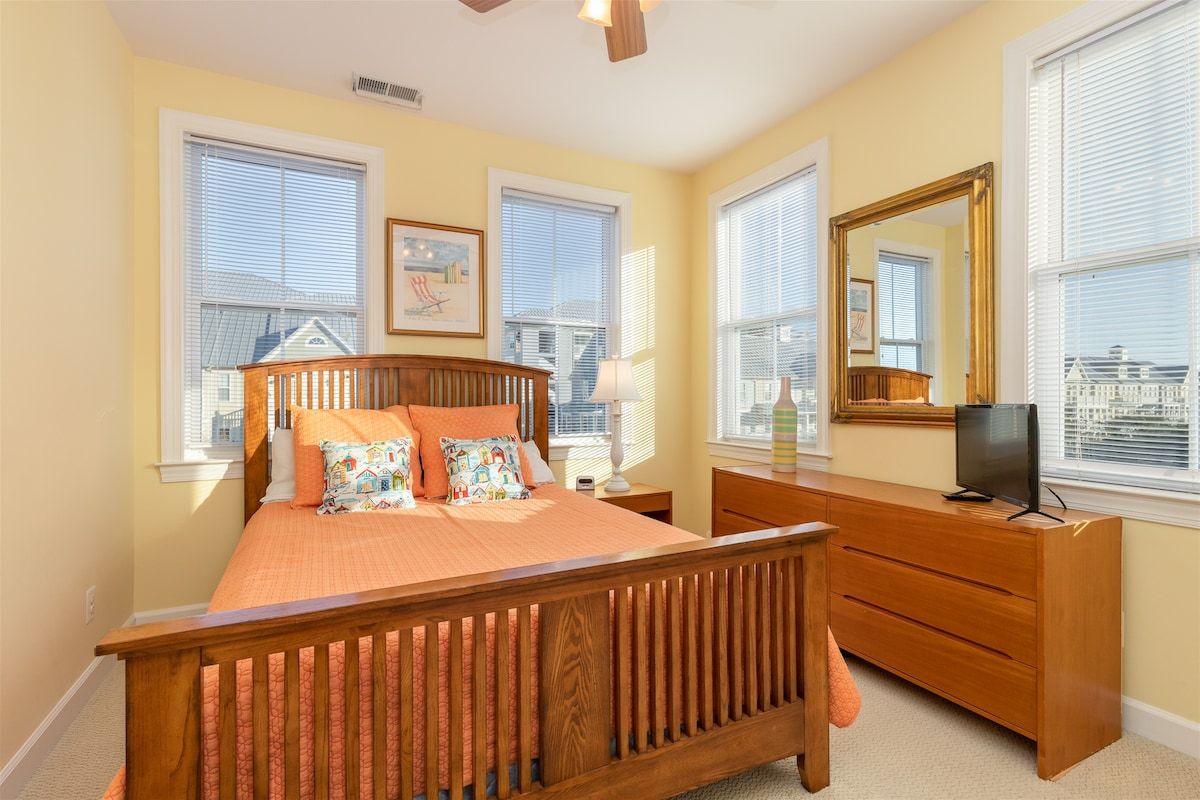 Une chambre à coucher avec un lit en bois, une commode, un téléviseur et un grand miroir.