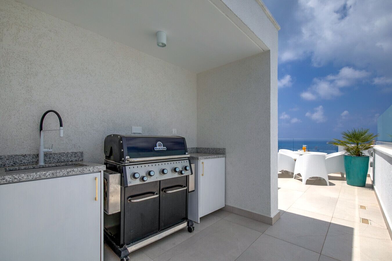 Une cuisine extérieure équipée d’un barbecue, d’un évier et offrant une vue sur l’océan.