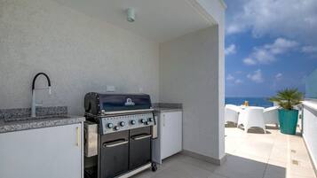 Une cuisine extérieure équipée d’un barbecue, d’un évier et offrant une vue sur l’océan.