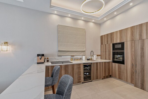 Una cocina moderna con armarios de madera, horno integrado y enfriador de vinos.