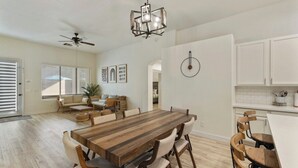A spacious kitchen with a large wooden dining table, white cabinetry, and a ceiling fan. - Chandler Hideaway - Relax & Unwind | Heated pool (Chandler)